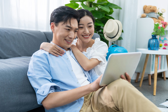 快乐的年轻情侣在客厅使用平板电脑