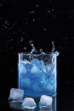 玻璃器皿中飞溅的蓝色液体与冰块