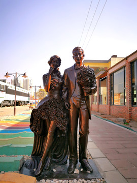 情侣在火车站拍婚纱雕塑