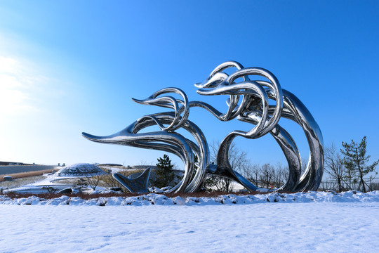 蓝天与雪地上的金属海豚雕塑