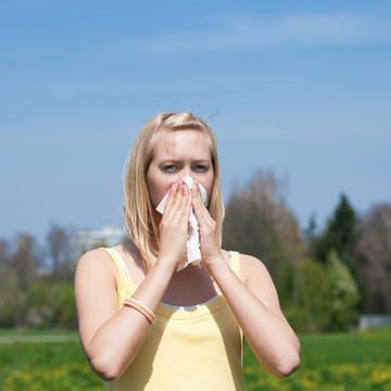 患流感或过敏的妇女在春天对着手帕打喷嚏