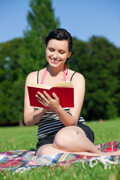 夏天坐在草地上晒太阳看书的女人