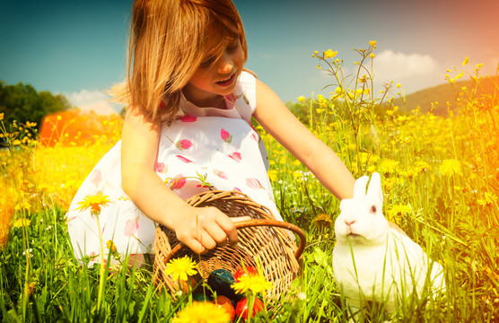 在草地上用鸡蛋抚摸复活节兔子的女孩-过滤图片