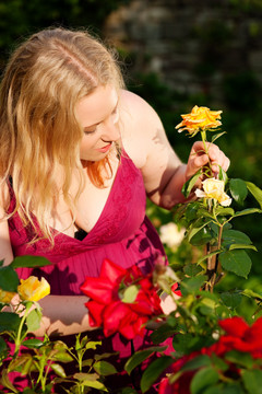 在阳光明媚的日子里，一个正在花园里修剪玫瑰的女人