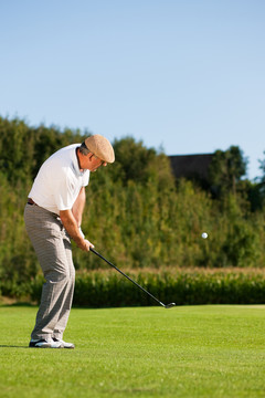一位高级高尔夫球手正在打高尔夫球，他正在一个美妙的夏日午后打球