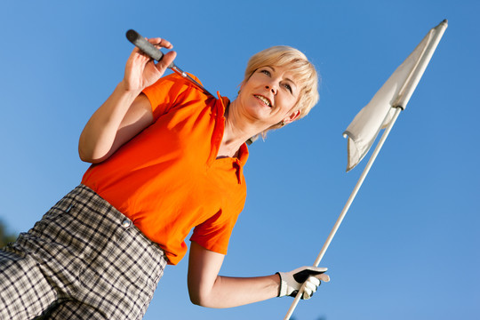 打高尔夫球的老妇人手里拿着旗子