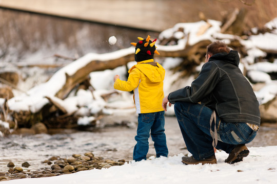 在冬季河岸边散步的一家人