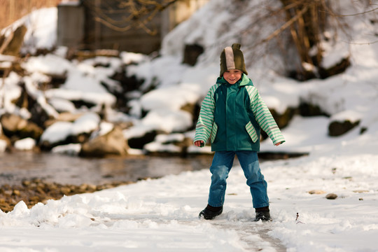 冬天在河岸上玩耍的小男孩