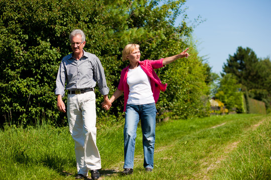明显快乐的成年或老年夫妇在户外手挽手散步