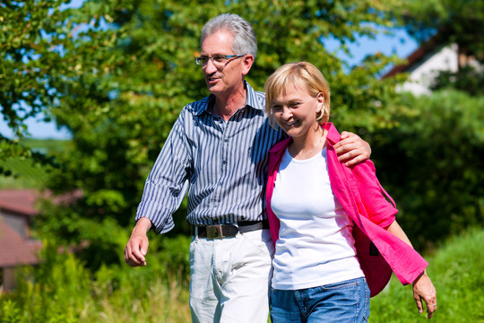 明显快乐的成年或老年夫妇在户外手挽手散步