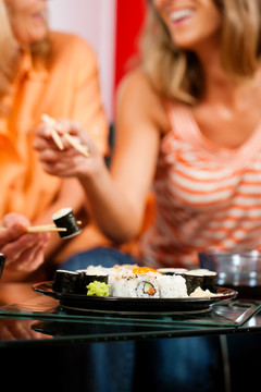 母亲和成年女儿在家吃寿司-重点是寿司盘