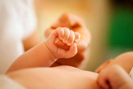 婴儿抓住照顾她的母亲的手（焦点在手上）