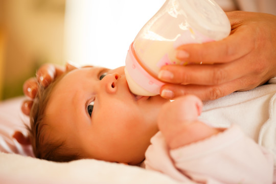 母亲-唯一能看到的手-正在用奶瓶喂她的孩子