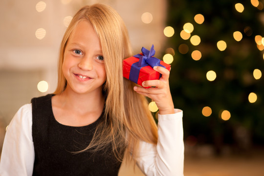 在圣诞树前拿着礼物的女孩