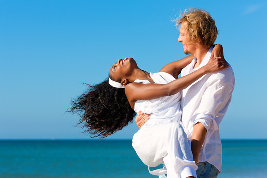 一对幸福的夫妇——黑人女人和白人男人——在海滩度假