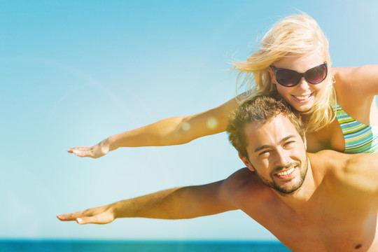度假海滩上的一对热恋情侣——男人背着妻子，背靠大海，他们感到明显的自由和快乐