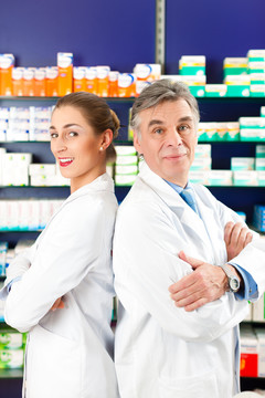 两个药剂师站在药房或药店的货架前拿着药品