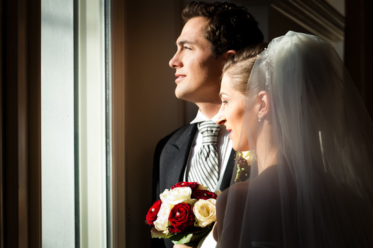新婚夫妇在婚礼上站在窗口向外看