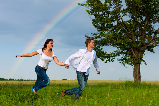 在草地上奔跑的幸福夫妻
