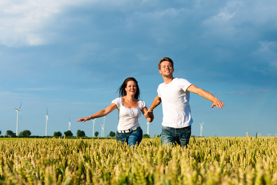 一对幸福的情侣手牵手在夏天的麦田上奔跑