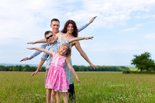 快乐的家庭-母亲，父亲，孩子们-站在蓝天下的草地上