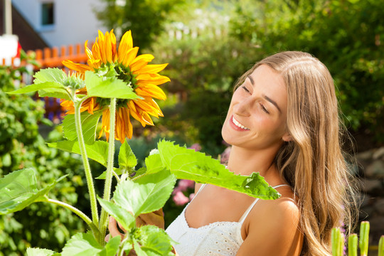 夏天的园艺-快乐的女人带着花在她的花园里
