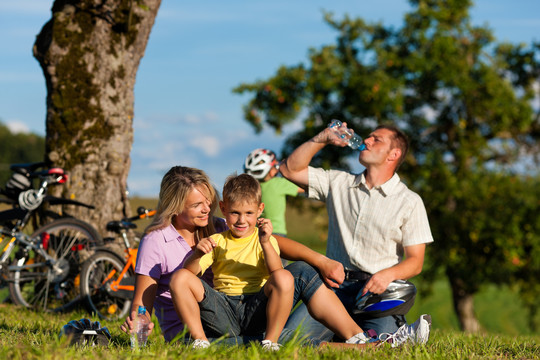 一个快乐的家庭（爸爸、妈妈和两个儿子）骑着自行车出游——他们有休息时间
