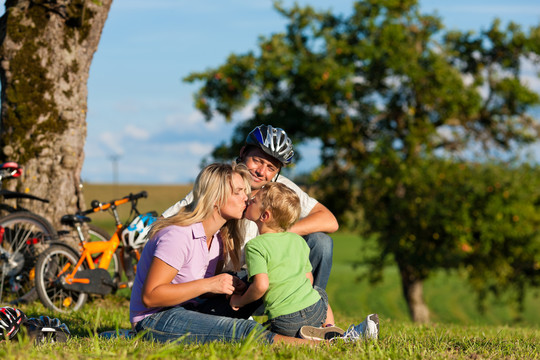 快乐的一家人（爸爸、妈妈和儿子）骑着自行车出游——他们有休息时间