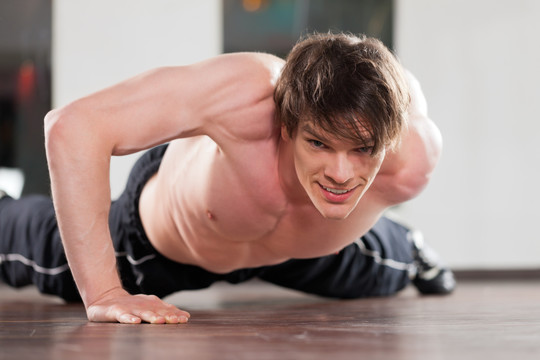 肌肉发达的男人在健身房里只用一只胳膊做俯卧撑