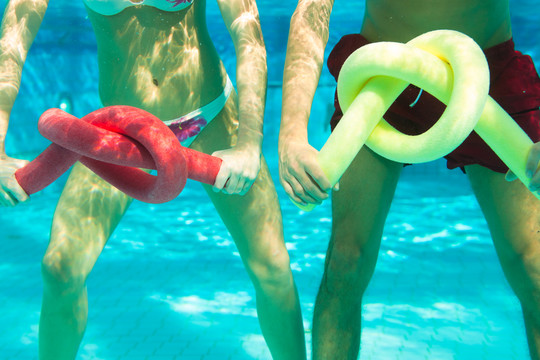 健身-一对年轻夫妇（男男女女）在游泳池或水疗中心用泳面在水下做运动和体操或水上有氧运动