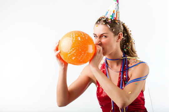 庆祝生日的女人在五彩纸屑雨中吹气球