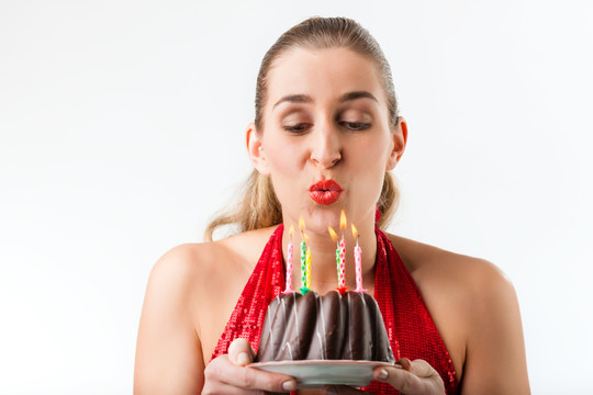 用蛋糕和蜡烛庆祝生日的女人，摄影棚拍摄的白色照片