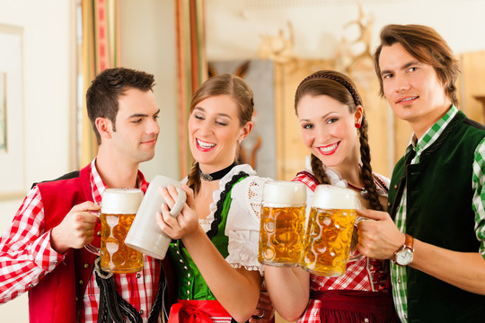年轻人在传统的巴伐利亚餐厅或酒吧里喝啤酒和啤酒