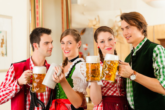 年轻人在传统的巴伐利亚餐厅或酒吧里喝啤酒和啤酒