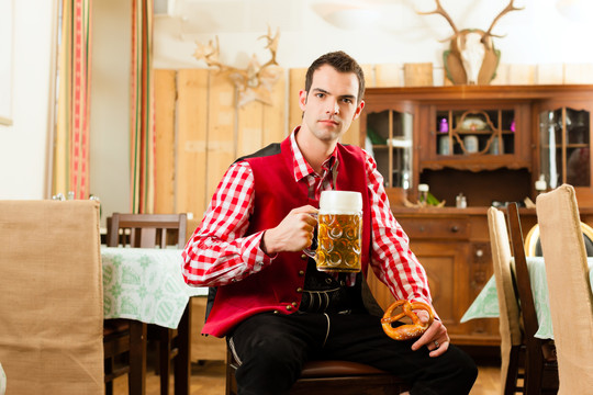 年轻人在传统的巴伐利亚餐馆或酒吧里喝着啤酒、啤酒和椒盐卷饼