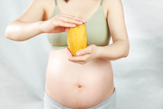 孕妇手上拿着一个芒果