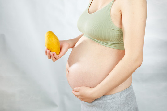 孕妇手上拿着一个新鲜芒果
