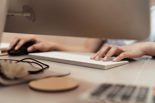 女人的手在键盘上打字。在现代办公环境中，商务人员手拿白键盘在网上搜索信息数据。