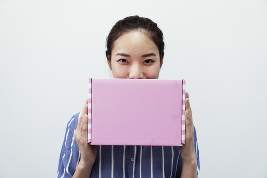 快乐的亚泰女人，白色背景上有一个粉红色的礼品盒。美丽与时尚。