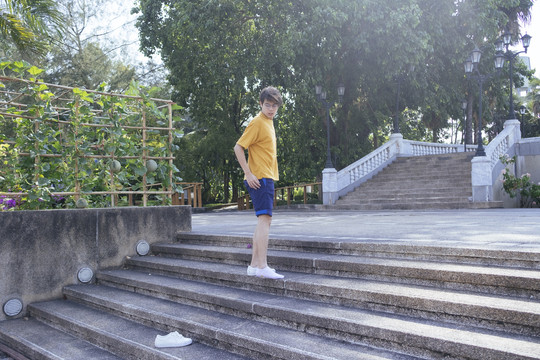 一个穿着黄色t恤和蓝色裤子的家伙走上鹅卵石楼梯，把鞋子扔在后面，横着走。