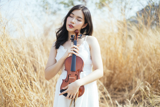 草原上，一位黑色卷发女子紧抱着心爱的小提琴。