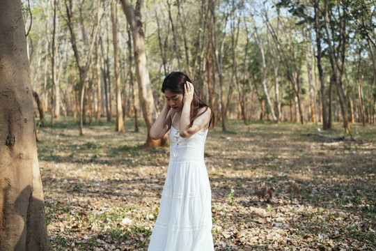 穿着优雅的白色连衣裙的漂亮年轻女子用手捂住耳朵。头痛和偏头痛。