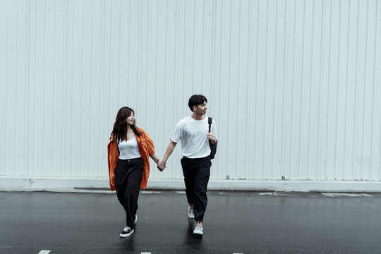 一对年轻的夫妇一起走过马路，手牵着手。