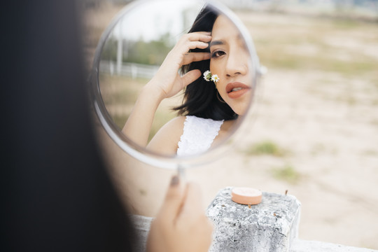 亚洲女人在户外小镜子上化妆的特写镜头。