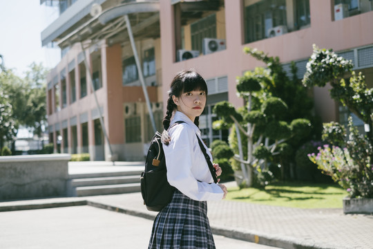 学生女孩站在学校大楼前的肖像照。
