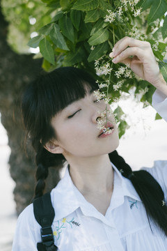 留着辫子和流苏头发的女学生抓着白花闻了闻。