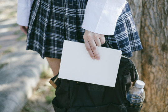 学生女孩手持笔记本和背包的裁剪图像。