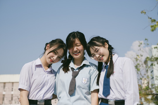三个穿着不同制服的美丽亚泰学生对着镜头微笑的画像。