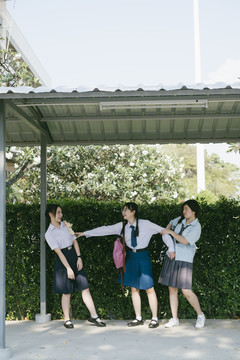 三个穿着不同制服的漂亮亚泰学生在学校里争吵。