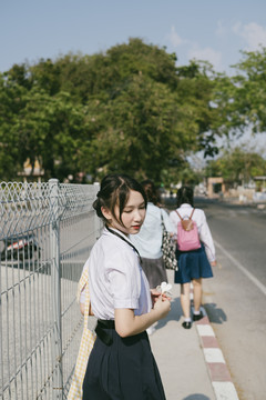 美丽的泰国学生在人行道上走在两个朋友后面的画像。